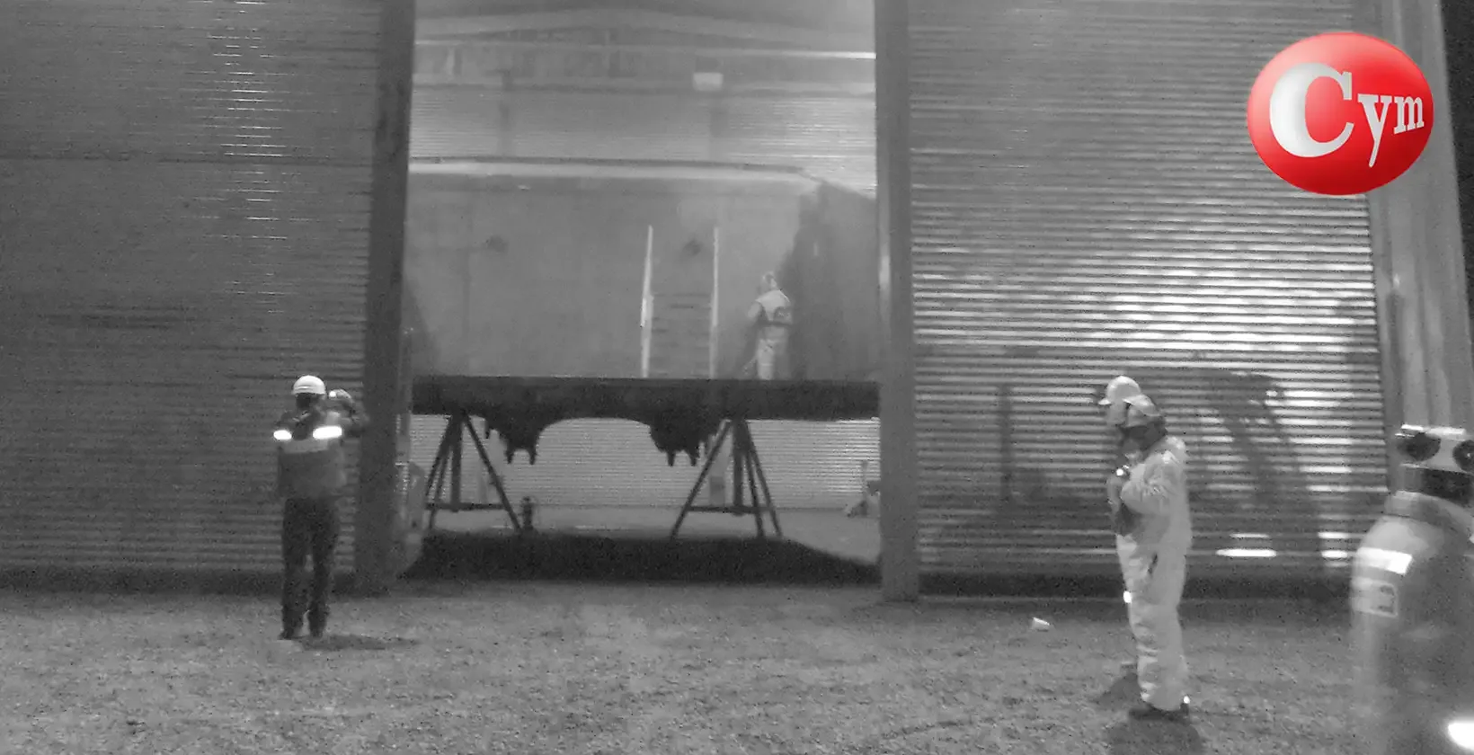 Vista nocturna cuarto granallado CYM Materiales — tolva volcadora camión minero — operario en altura Chile