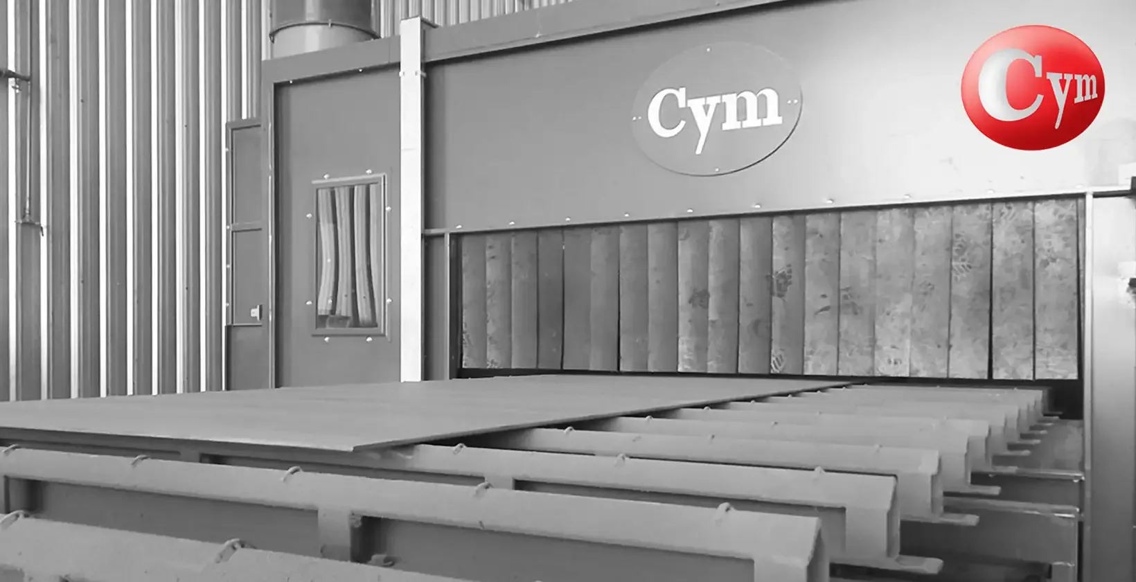 Salida del horno de secado de shop primer en línea CYM CH 2.5H – chapas de acero con imprimación gris sobre transportador de cadena · Astillero Paraná Sur, Argentina