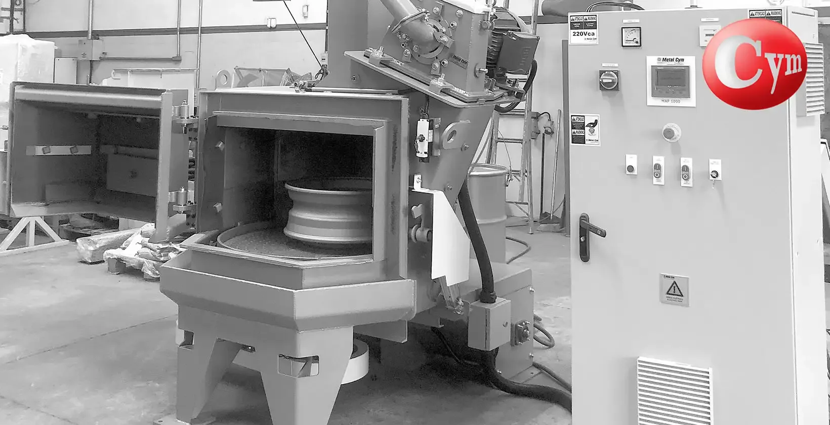 Granalladora de mesa giratoria CYM — llanta de aluminio sobre mesa — puerta abatible abierta — tablero CYM Argentina